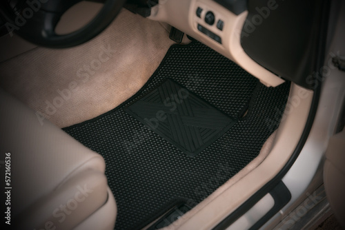 Driver-side black floor mats made of ethylene vinyl acetate shortened for EVA. Dark floor mats in the light interior of the car. photo