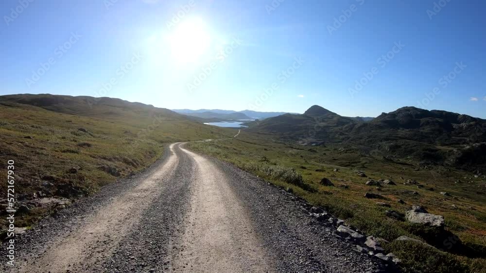 Moving shot of a cyclist passing by and waving on a bicycle in the mountains at high speed on a country road in Norway. Moving shot of a cyclist passing by and waving on a bicycle in the mountains at high speed on a country road in Norway.