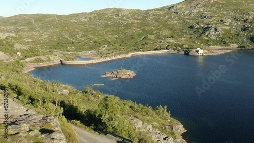 Aerial reveal shot of an electric power plant located on the dam in Norway on a sunny day. photo