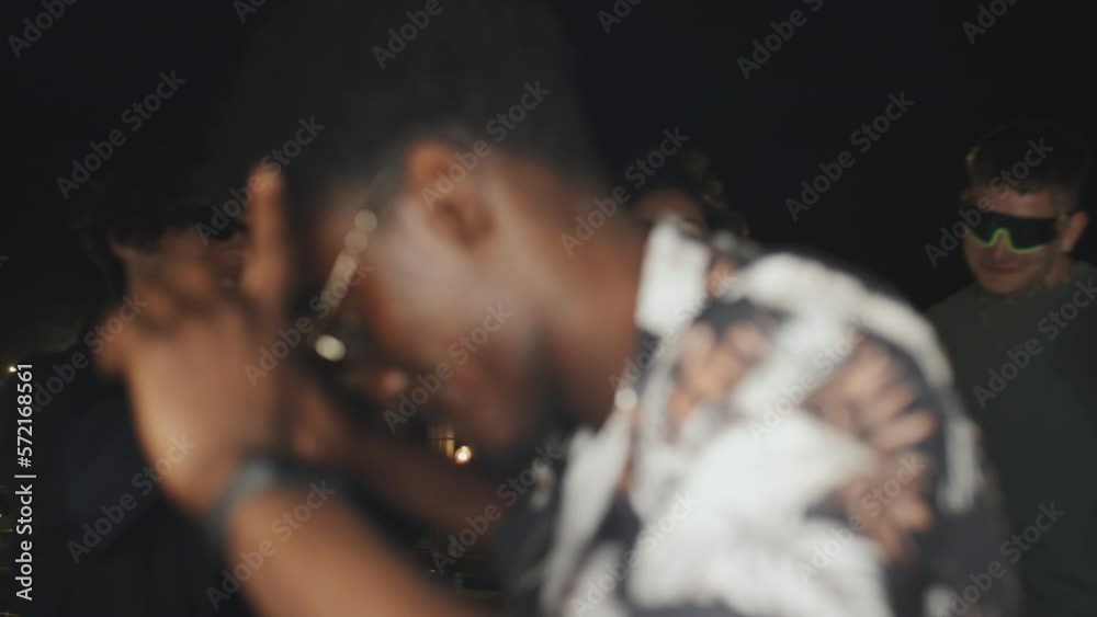 Handheld shot of stylish young African American man dancing with his friends at rooftop party on summer night Handheld shot of stylish young African American man dancing with his friends at rooftop party on summer night