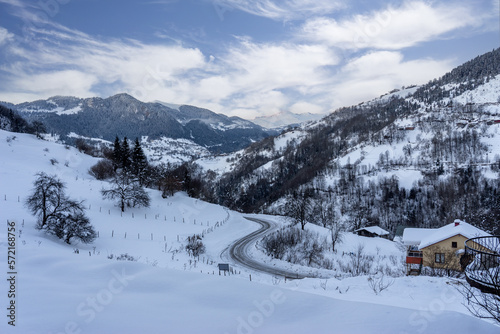 Snowy winter day, winding road landscape and clouds. © klenger