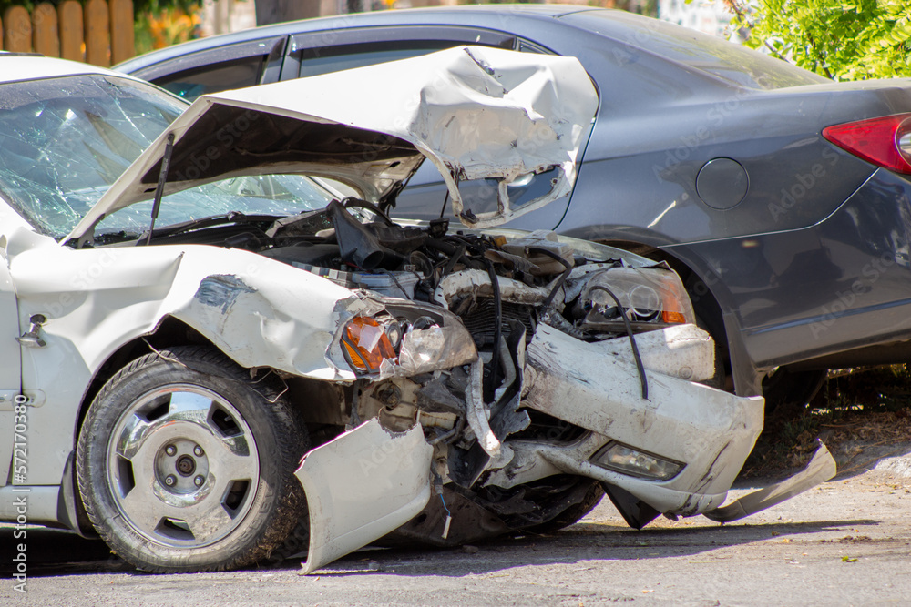 Two cars on the road after a collision. Road adventure and broken bumper, hood, headlights and fender on a white car.