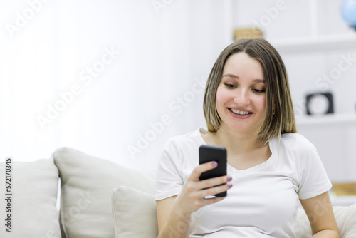 Close-up photo of beautiful pregnant woman looking at the phone.