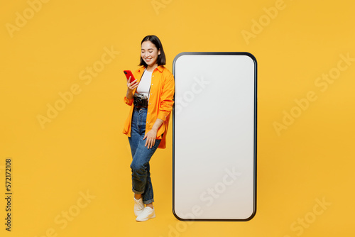 Young woman wear summer clothes big blank screen mobile cell phone use smartphone isolated on plain yellow background. Tourist travel abroad in free time rest getaway. Air flight trip journey concept.