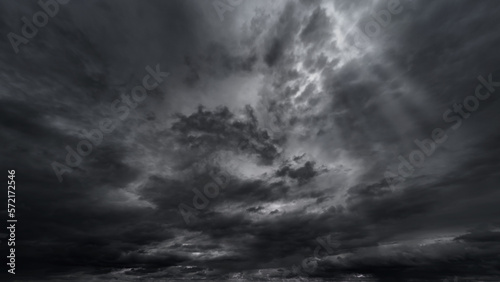 dark dramatic sky with black stormy clouds before rain or snow as abstract background, extreme weather, the sun shines through the clouds, high contrast photo