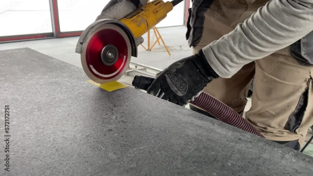 Builder tiler measures the tiles and cuts them with a diamond cutter Builder tiler measures the tiles and cuts them with a diamond cutter