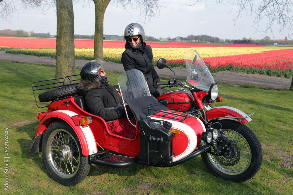 Two young women sharing a moment while sitting in a red motorcycle Two young women sharing a moment while sitting in a red motorcycle