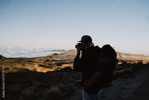Upper body of a male hiker taking a photo of volcanic landscape