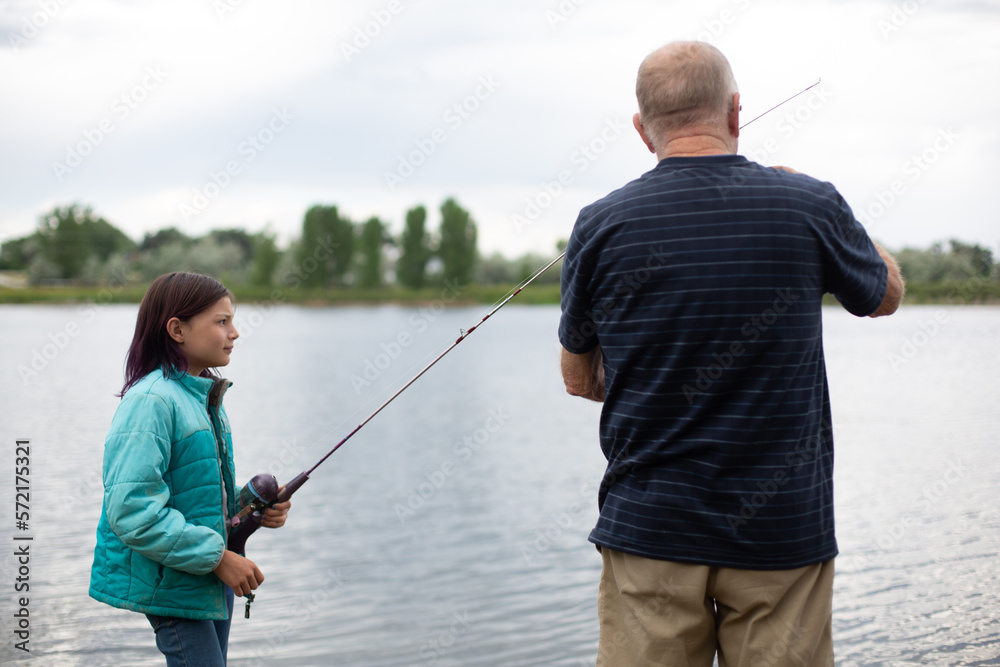 Grandfather helping granddaughter with her fishing pole Grandfather helping granddaughter with her fishing pole