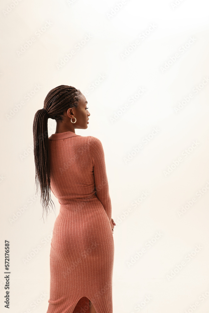 Fototapeta premium Back view shot of young and beautiful woman posing over white wall. Vertical.