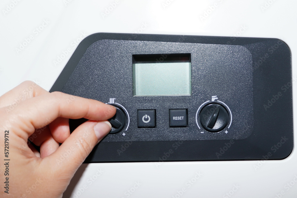 Obraz premium Woman checking settings and temperature on the gas boiler at home.