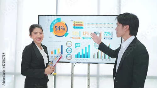 Two professional asian businesspeople presentation company growth data strategy on televition for explain at office workshop meeting photo