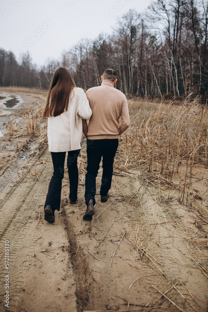 a man and a woman are walking along the shore of the lake, cold foggy weather. romantic photo in beige tones. holding a woman's hand, a love story. beige sweaters. romantic photos by the lake a man and a woman are walking along the shore of the lake, cold foggy weather. romantic photo in beige tones. holding a woman's hand, a love story. beige sweaters. romantic photos by the lake