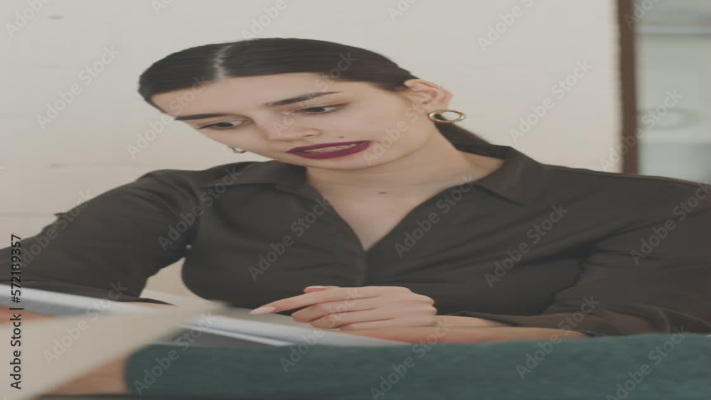 Vertical shot of young Middle Eastern woman and her male colleague analyzing financial report at office meeting Vertical shot of young Middle Eastern woman and her male colleague analyzing financial report at office meeting