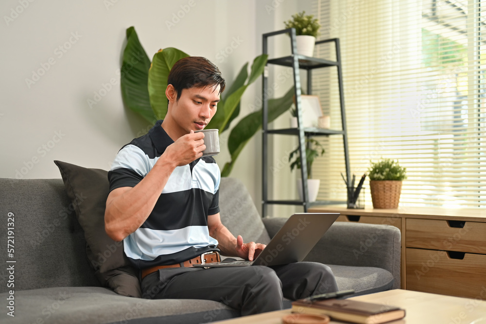 Handsome asian man looking at screen, watching video or surfing internet in comfortable home Handsome asian man looking at screen, watching video or surfing internet in comfortable home
