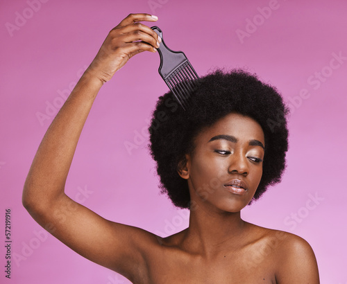 Black woman, hairstyle or afro brushing on beauty studio background in relax grooming routine, texture maintenance or wellness. Model, comb or natural hair growth and skincare makeup on isolated pink
