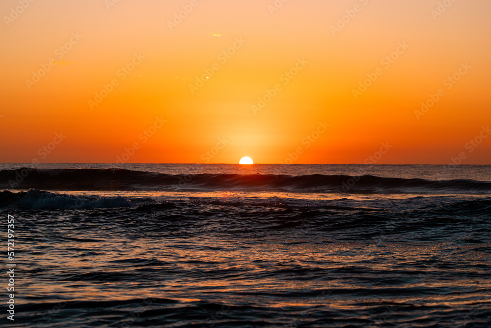 Sunrise from ocean horizon with clear sky.