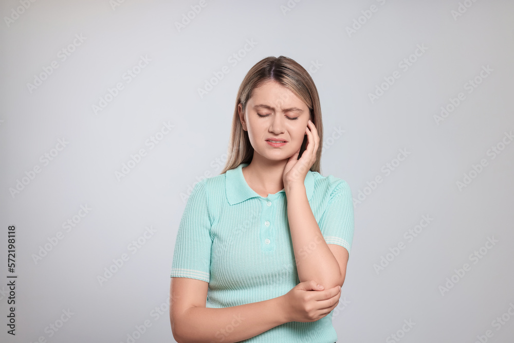 Young woman suffering from ear pain on light grey background Young woman suffering from ear pain on light grey background