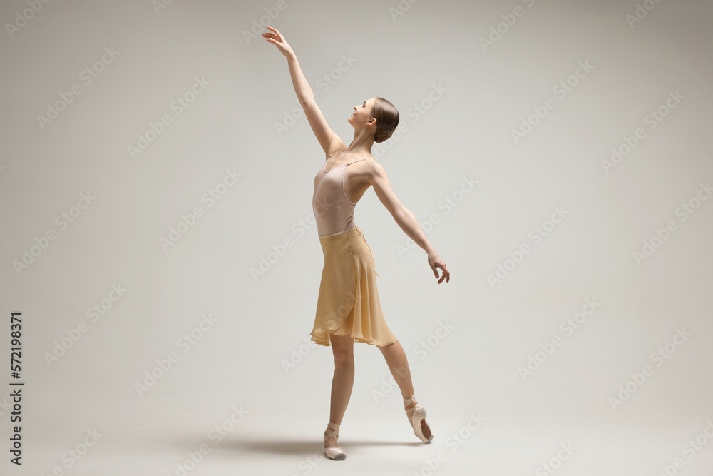 Young ballerina practicing dance moves on light grey background Young ballerina practicing dance moves on light grey background