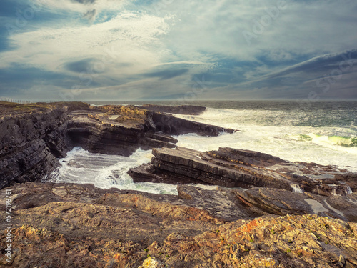 Spectacular Irish seascape with rough stone coast line and powerful Atlantic ocean. Kilkee area, Ireland. Dramatic sky. Detailed nature scene.