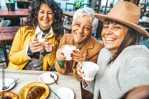 Three senior women enjoying breakfast drinking coffee at bar cafeteria - Life style concept with mature female taking selfie picture with smart mobile phone device