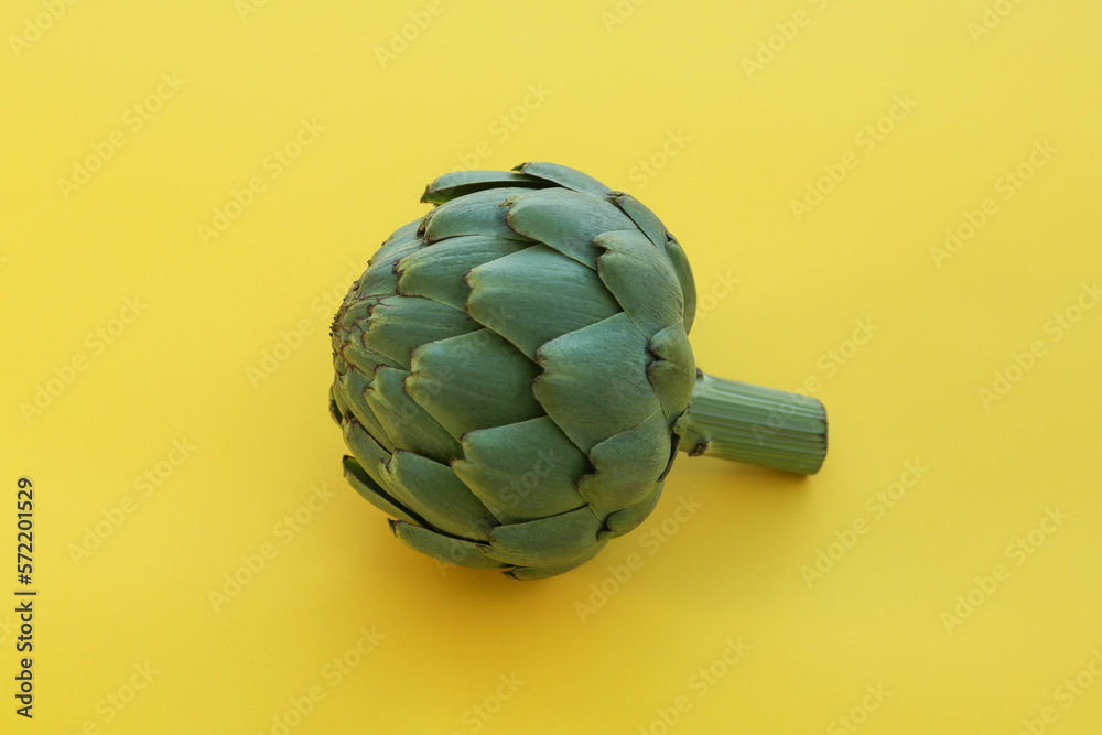 Fototapeta premium Whole fresh raw artichoke on yellow background, closeup