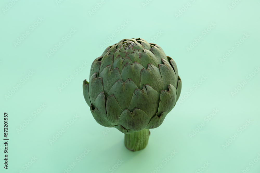 Fototapeta premium Whole fresh raw artichoke on green background, closeup