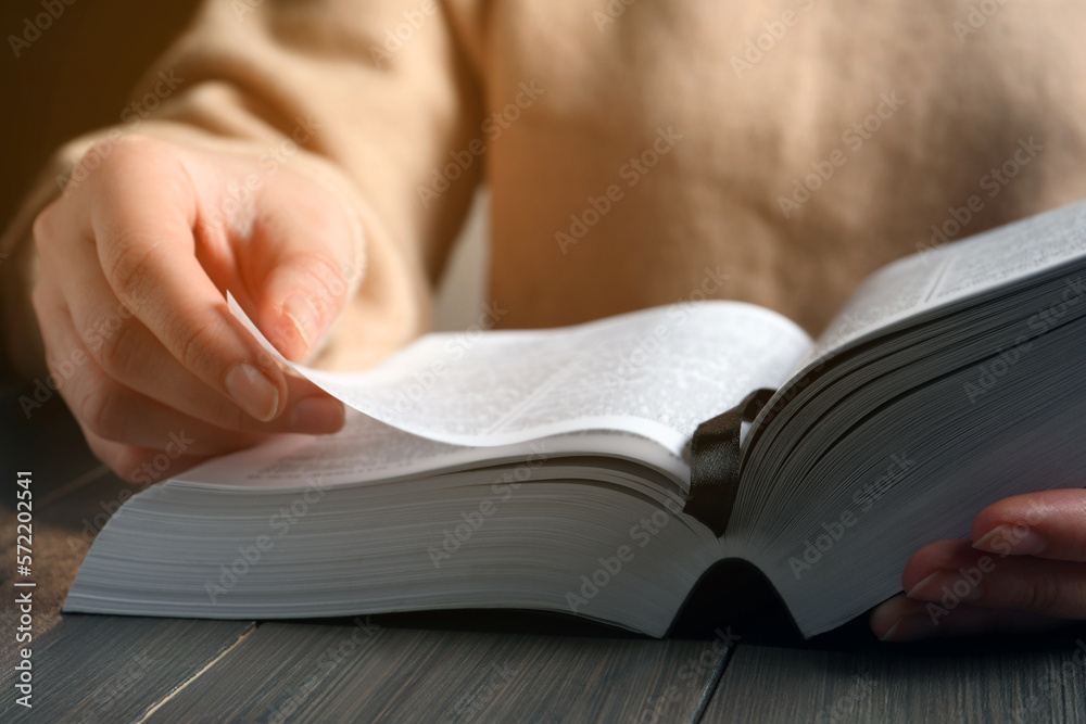 Woman reading Bible at wooden table, closeup Woman reading Bible at wooden table, closeup