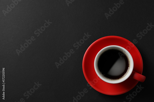 Cup with aromatic coffee on black background, top view. Space for text