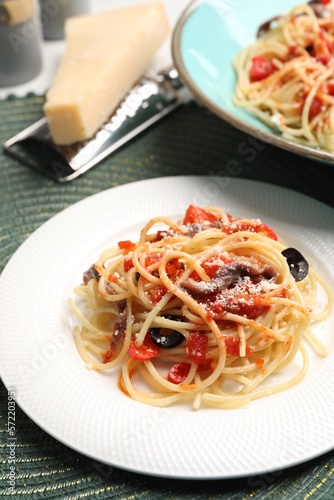 Delicious pasta with anchovies, tomatoes and parmesan cheese served on table, closeup