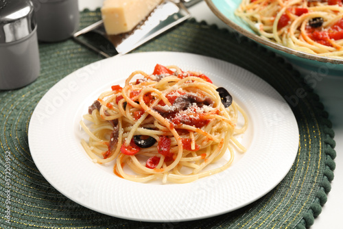 Delicious pasta with anchovies, tomatoes and parmesan cheese served on white table