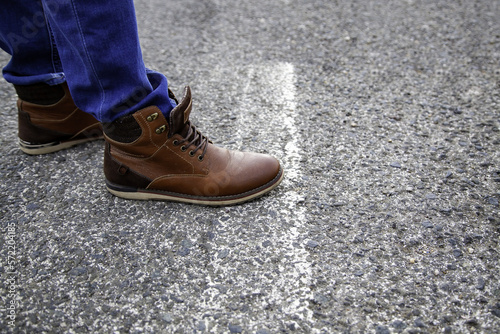 Feet stepping on asphalt line