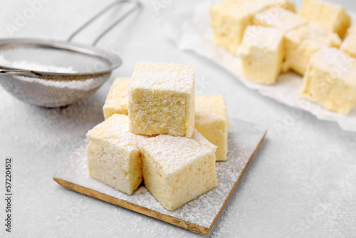 Delicious sweet marshmallows with powdered sugar on light grey table