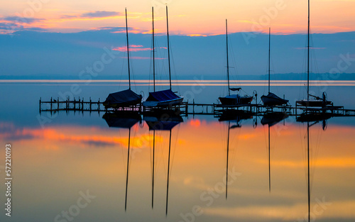 Photograph of a fishing village in the sea, with the background of the sun, red evening sky, blue sea. Refleksies op die oppervlak van die water