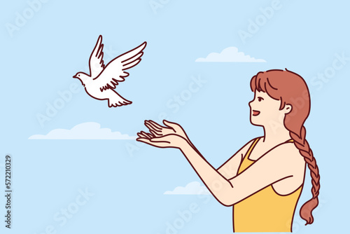 Little girl volunteers teenager sets dove free and lets bird fly towards sky for family reunion. Dove symbolizes peace and prosperity or activism to protect animal birds locked in cages 