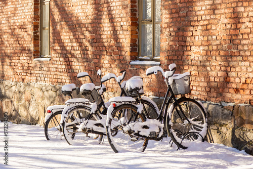 Bicycles left in a parking spot with a thick layer of fresh snow.