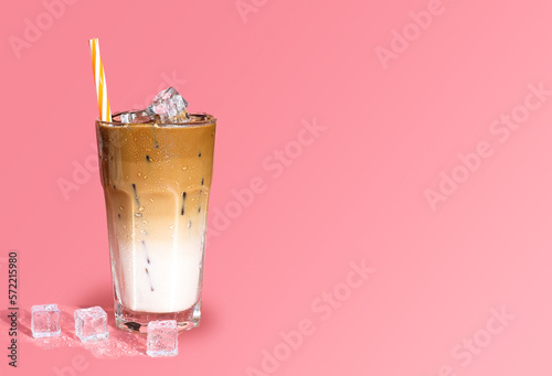 Summer drink background, copy space. Glass of sweet creamy iced coffee , espresso coffee with milk with straw isolated on pink background.	 photo