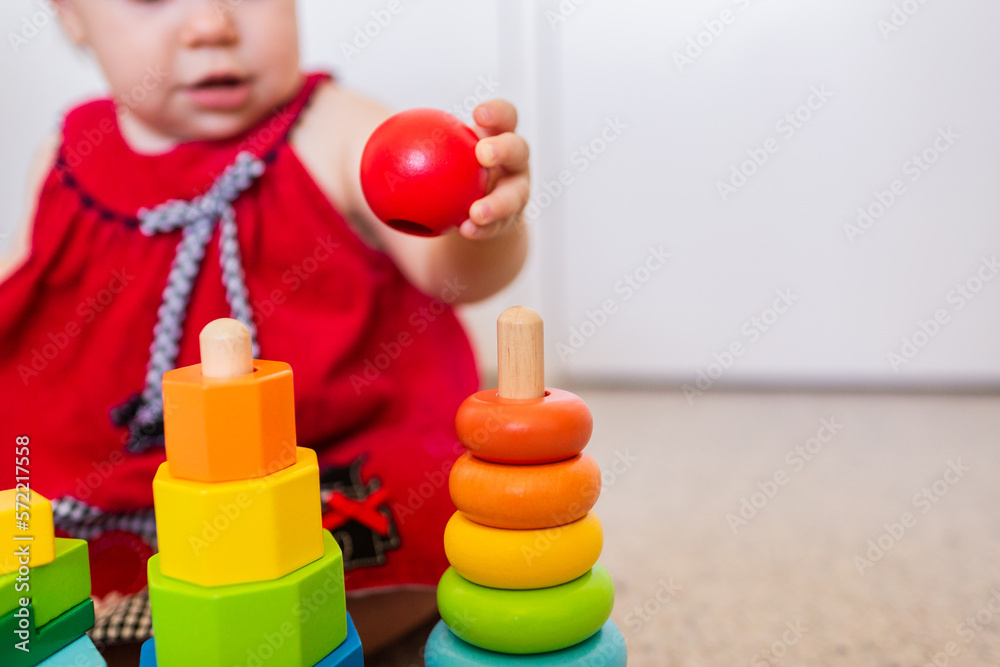 Baby sitting on floor playing with colourful stacking fine motor skills developmental toy