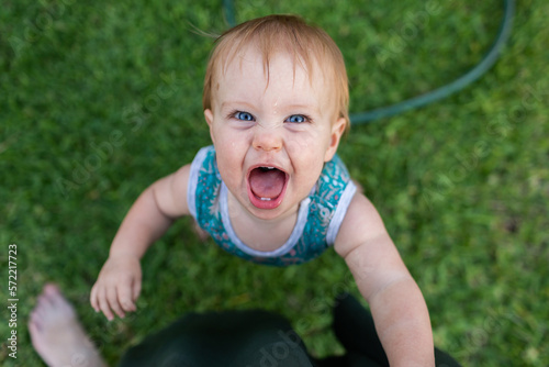 Baby with huge smile looking up at mum while pulling up to stand photo