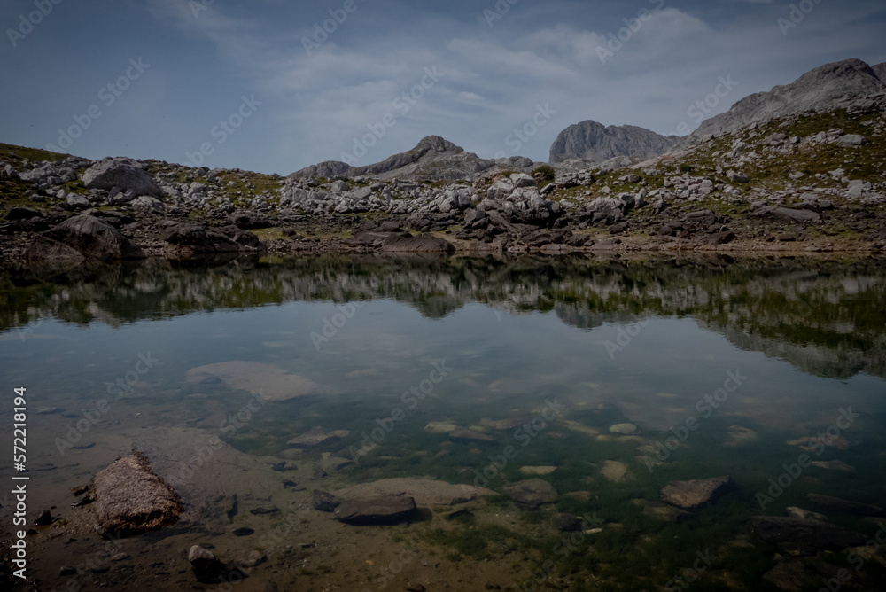 Fototapeta premium Charca protegida con reflejo de la montaña y mas montaña de fondo.