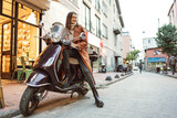 Portrait of attractive young cheerful woman riding moped scooter