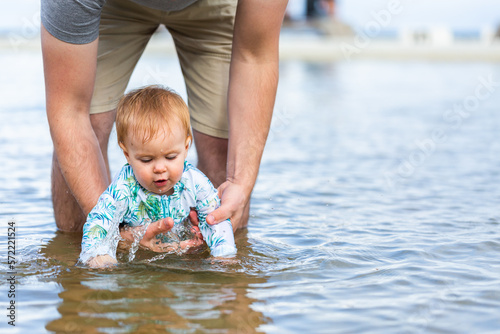 Parent in the water with baby splashing at the seaside photo