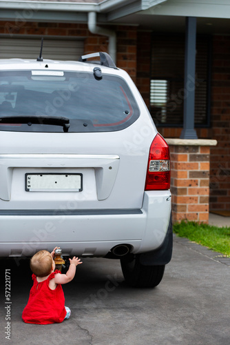 Baby playing with tow ball of parked car in unsafe situation photo