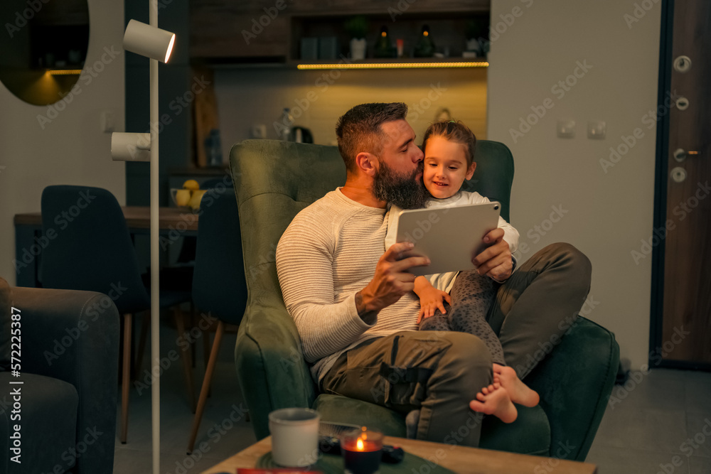 Father and daughter being cuddly, dad is kissing daughter on a cheek Father and daughter being cuddly, dad is kissing daughter on a cheek