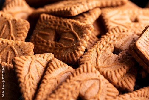 A pile of multiple brown cookies called speculoos or speculaas in Belgium or the Netherlangs. The spiced biscuit is very delicious and popular during the winter period to be eaten at any time.