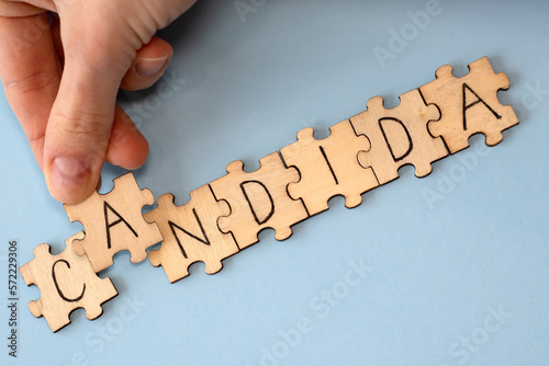 Photos Candida is a word of wooden puzzles with letters, the concept of the parasitic fungus candida, blue background