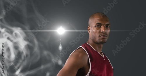 Portrait of african american male athlete against smoke effect and light spot on grey background