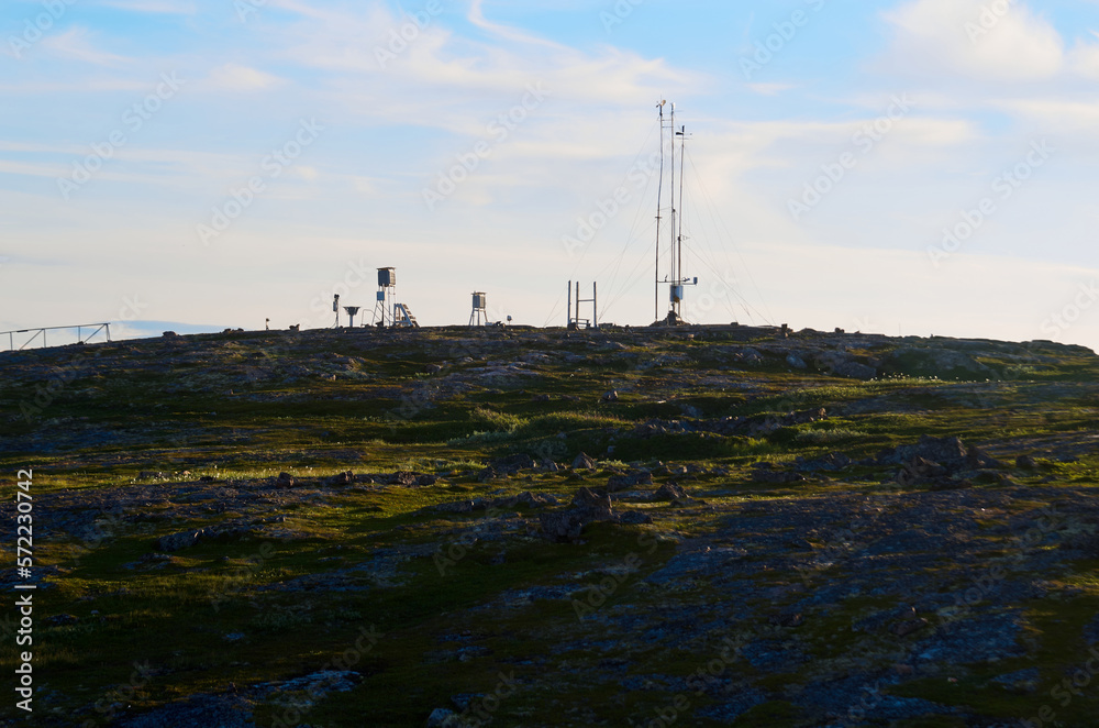 Meteorological station on a green rocky mountainside on a cloudy day