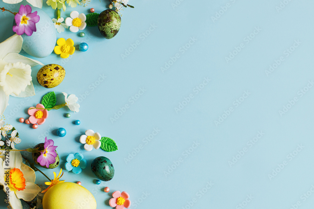 Stylish easter eggs, candy and blooming flowers on blue background flat lay. Happy Easter! Natural painted colorful eggs and spring blossom. Modern greeting card or banner, copy space Stylish easter eggs, candy and blooming flowers on blue background flat lay. Happy Easter! Natural painted colorful eggs and spring blossom. Modern greeting card or banner, copy space