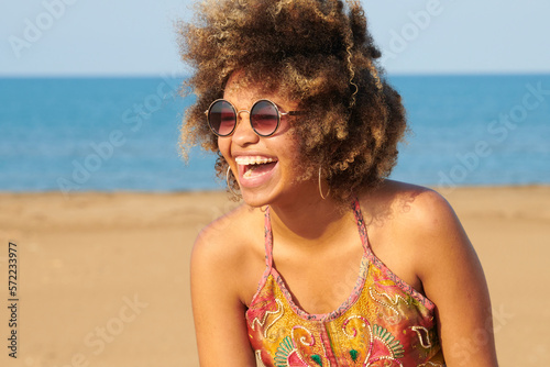 Laughing girl with frizzy hair on the beach. Portrait of happy woman with brackets and frizzy hair laughing on sunny beach.